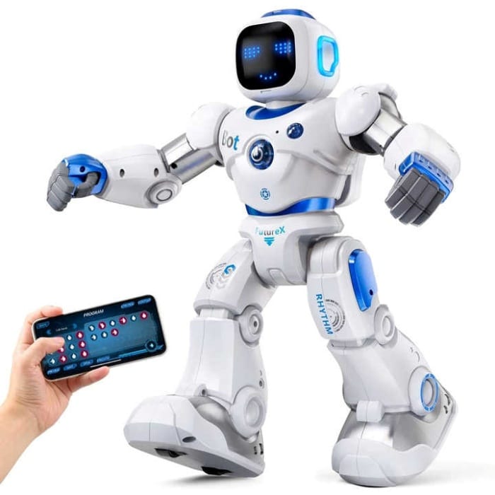 Here is a description of the image: The image shows a white and blue robot toy. The robot is bipedal and has articulated arms and legs. It has a screen on its head that displays a smiley face. The robot is being controlled by a smartphone. The smartphone has a program interface with buttons for controlling the robot's movements.